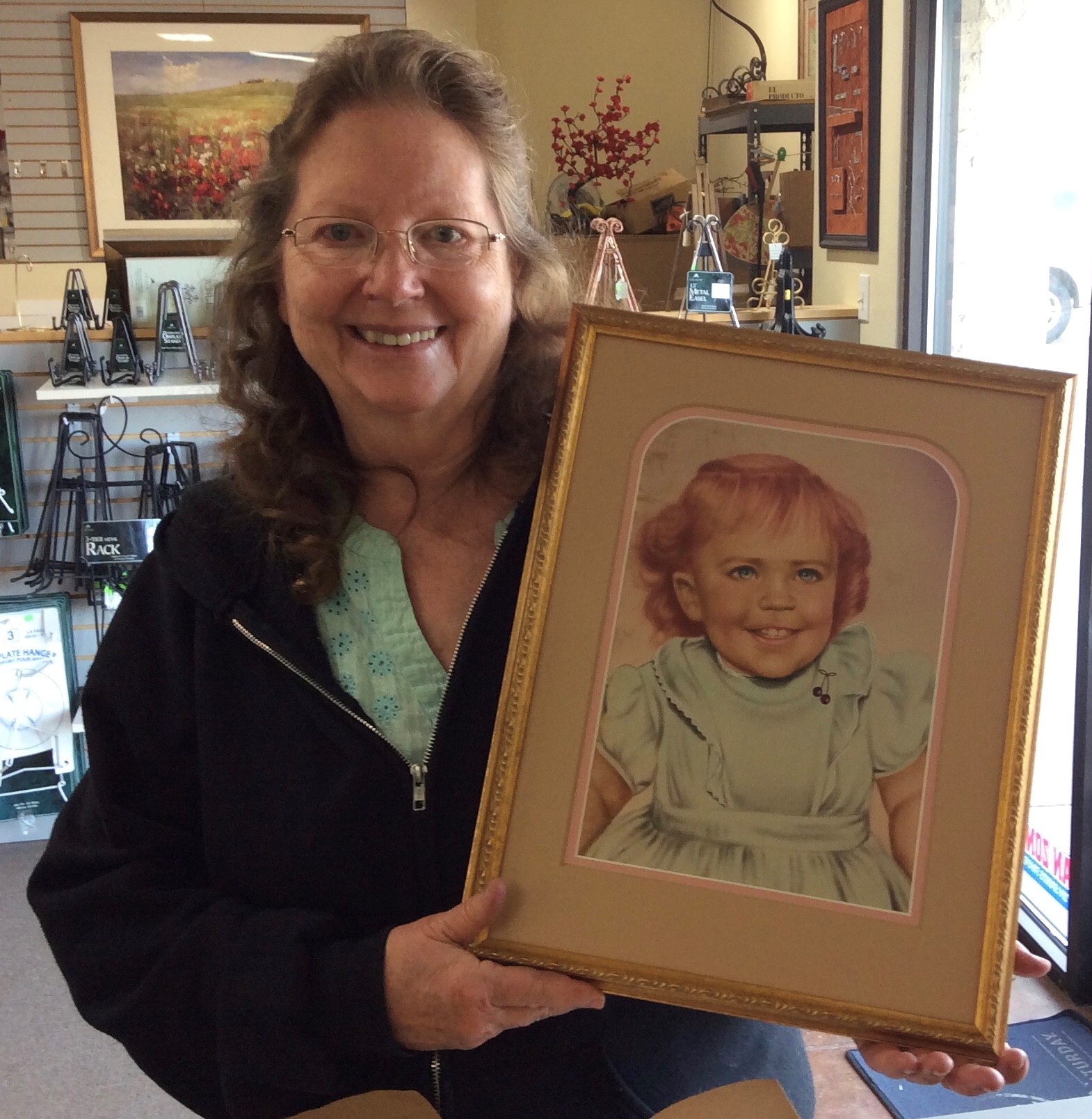 Woman holding framed drawing of girl